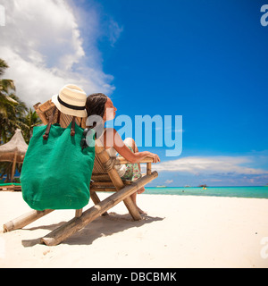 Nice woman relaxing in la chaise en bois sur la plage blanche Banque D'Images