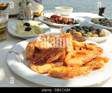 Taverne au bord de l'eau table des crevettes, calamars à la sauce tomate, olives et houmous en sauce au citron, Gikes,Péloponnèse , Grèce Banque D'Images