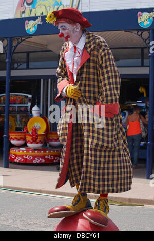 Swanage, Dorset Royaume-Uni 28 juillet 2013. Des milliers de visiteurs descendent sur Swanage pour assister à la procession, dans le cadre de la semaine du carnaval de Swanage. Clown divertissant la foule debout sur le ballon avec de grandes chaussures. Crédit : Carolyn Jenkins/Alay Live News Banque D'Images