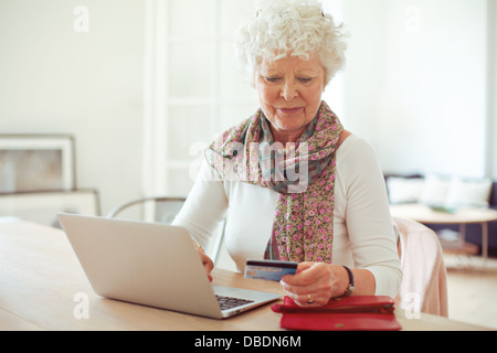 Grand-mère à l'avant du coffre de payer en ligne en utilisant une carte de crédit Banque D'Images