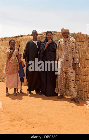 Groupe de villageois maliens du nord est du Mali en vêtements traditionnels en face de cadre en bois tapis tissés hut, Afrique de l'Ouest Banque D'Images