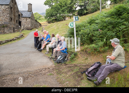 Groupe de randonneurs en appui sur un mur par un sentier enseigne sur une promenade dans le parc national de Snowdonia, Gwynedd, au nord du Pays de Galles, Royaume-Uni Banque D'Images