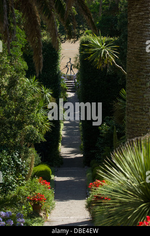 En regardant une avenue de plantes vers une statue en bronze appelé enfants Tresco par David Wynne , Jardin de l'abbaye de Tresco, Tresco, Îles Scilly, Angleterre Banque D'Images