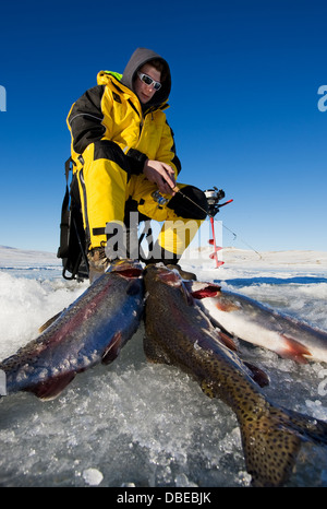 Pêcheur sur glace avec sa pêche de la truite sur la glace Banque D'Images