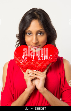 Young woman holding red heart-shaped oreiller sous face pour la Saint Valentin Banque D'Images