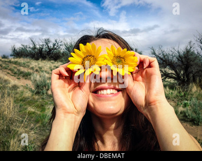 Caucasian woman holding Flowers sur ses yeux Banque D'Images