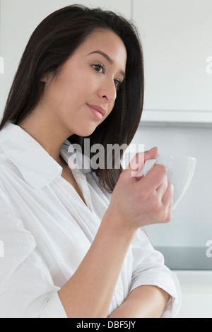 Mixed Race woman having tasse de café dans la cuisine Banque D'Images