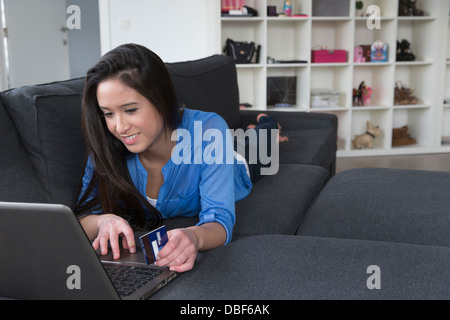 Mixed Race woman shopping online sur canapé Banque D'Images