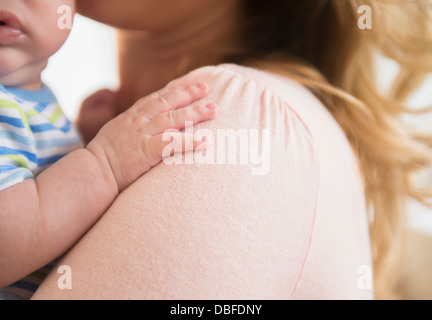 Caucasian baby's main sur l'épaule de la mère Banque D'Images