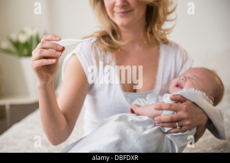 Mère de race blanche prendre la température du bébé qui pleure Banque D'Images