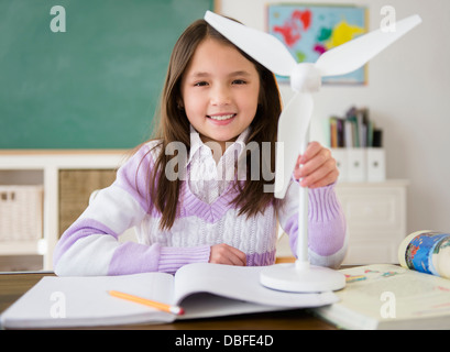 Mixed Race girl holding model wind turbine in class Banque D'Images