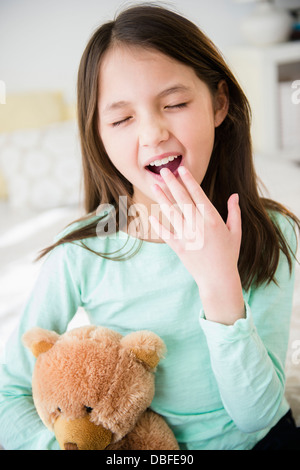 Mixed Race girl with teddy bear le bâillement Banque D'Images