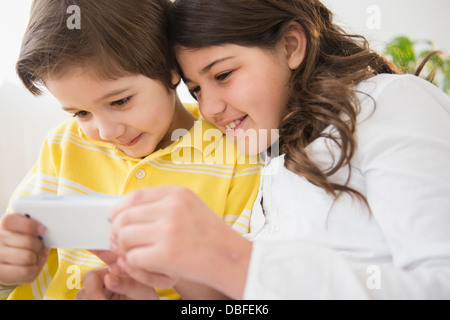 Les enfants hispaniques utilisant cell phone together Banque D'Images