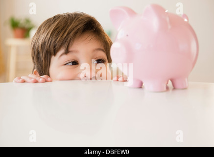 Boy examinant piggy bank Banque D'Images