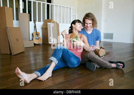 Couple eating take out food in new home Banque D'Images