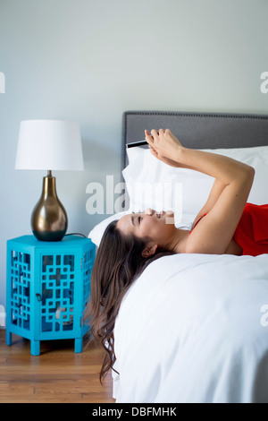 Japanese woman using cell phone on bed Banque D'Images