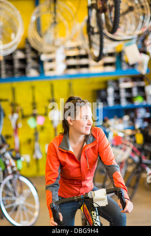 Caucasian woman sitting in Bicycle shop Banque D'Images