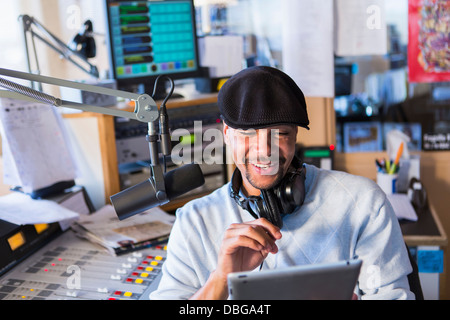 Mixed Race disc jockey using tablet computer in studio Banque D'Images