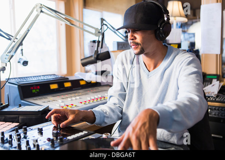 Mixed Race disc-jockey à l'aide de studio en platine Banque D'Images