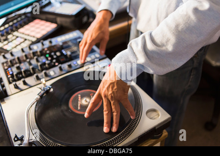 Mixed Race disc-jockey à l'aide de studio en platine Banque D'Images