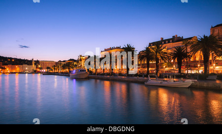 Les bateaux sont amarrés le long de la Riva à Split, Croatie, bordée de palmiers, avec les lumières reflétées dans la mer Adriatique Banque D'Images