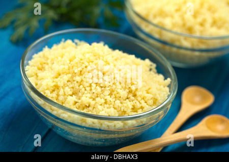 Couscous préparé dans bol en verre sur la surface en bois bleu avec du persil dans le dos Banque D'Images