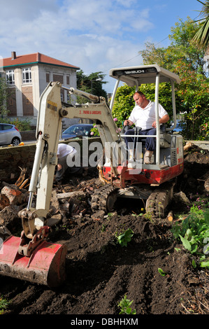 Mini digger dépose de la terre, dans le jardin intérieur Banque D'Images