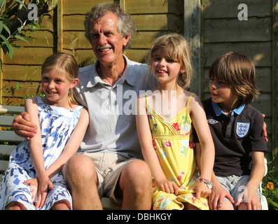 Grand-père avec ses petits-enfants assis sur un banc Smiling In jardin en été Birmingham West Midlands England Banque D'Images