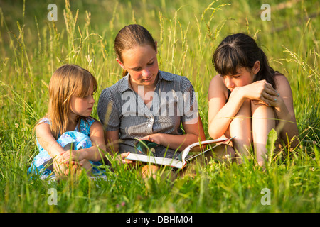 Enfants lecture livre sur l'ensemble du parc. Banque D'Images