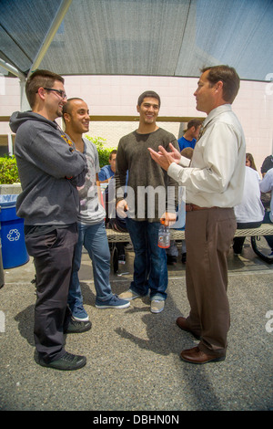 Un directeur de l'école entretiens avec trois étudiants masculins sur le campus de banlieue à l'heure du déjeuner dans la région de Aliso Viejo, CA. Banque D'Images