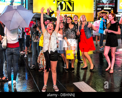 Happy teen girls watch danse eux-mêmes une caméra de télévision avant de projeter leur image sur un écran géant Banque D'Images