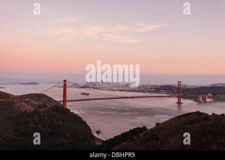 Golden Gate Bridge dans la lueur rose du crépuscule vue des montagnes sur le côté nord de pont avec des toits de la ville en arrière-plan Banque D'Images