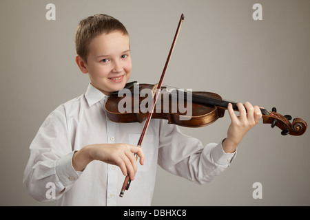 Adolescent à jouer du violon, fond gris Banque D'Images