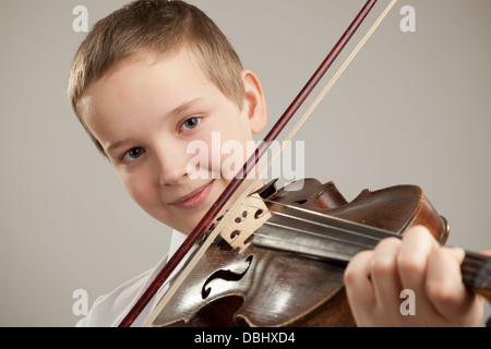 Adolescent à jouer du violon, fond gris Banque D'Images