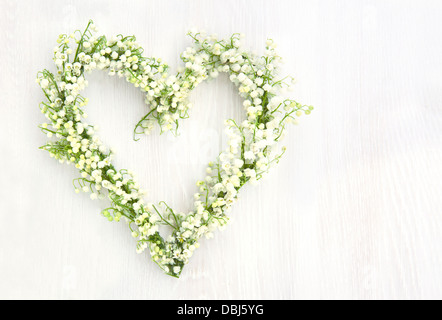 Guirlande de fleurs en forme de coeur de lilys valley sur fond de bois blanc Banque D'Images