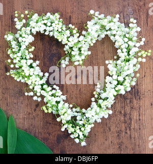 Guirlande de fleurs en forme de coeur lilys de la vallée sur fond de bois rustique Banque D'Images