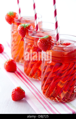 Verres de jus de fraise rouge avec glaçons congelés et des pailles à rayures vintage sur fond de bois et de serviette Banque D'Images
