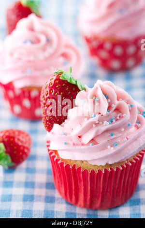 Cupcakes rose avec des fraises fraîches et saupoudre sur une serviette bleu vintage retro Banque D'Images