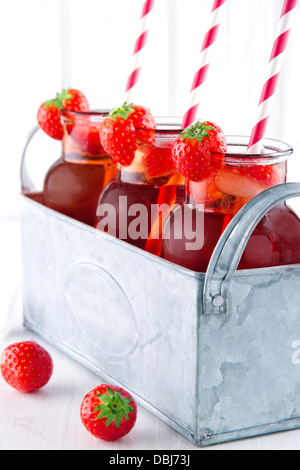 Verres de jus de fraise rouge avec glaçons congelés et pailles à rayures dans un récipient en métal vintage Banque D'Images