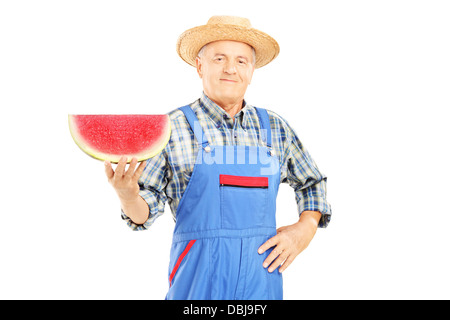 Smiling farmer en salopette tenant une tranche de pastèque et à ta caméra isolé sur fond blanc Banque D'Images