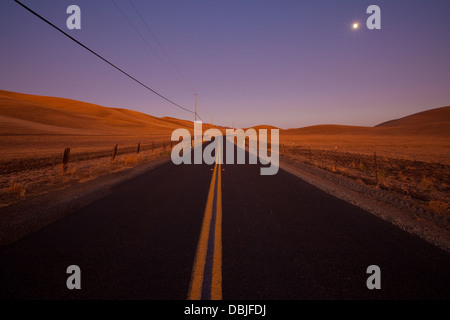 Route de campagne romantique de deux voies au crépuscule dans des terres agricoles pays idyllique - crépuscule / l'aube de l'éclairage. Banque D'Images