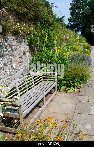 Dartington, Devon, Angleterre. Le 15 juillet 2013. Sentier et siège de jardin dans la cour de l'inclinaison de la frontière de Dartington Hall. Banque D'Images