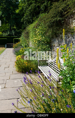 Dartington, Devon, Angleterre. Le 15 juillet 2013. Sentier et siège de jardin dans la cour de l'inclinaison de la frontière de Dartington Hall. Banque D'Images