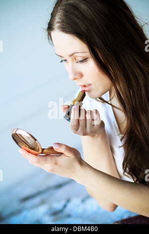 Woman putting on lipstick, à la main en miroir, Copenhague, Danemark Banque D'Images