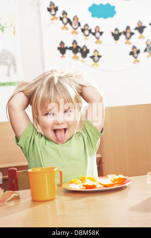 Girl at Table Sticking Out Tongue, Kottgeisering, Bavaria, Germany, Europe Banque D'Images