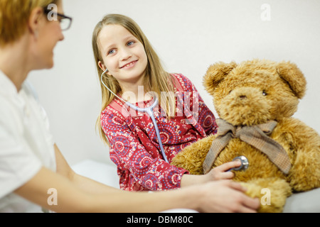 Jeune fille est à l'aide d'un stéthoscope ludique sur un ours en peluche, Osijek, Croatie Banque D'Images