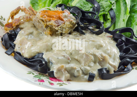 Tagliatelles noires (les pâtes faites avec de l'encre de seiche) avec sauce carbonara , poêlée de légumes frais et de crabe Banque D'Images