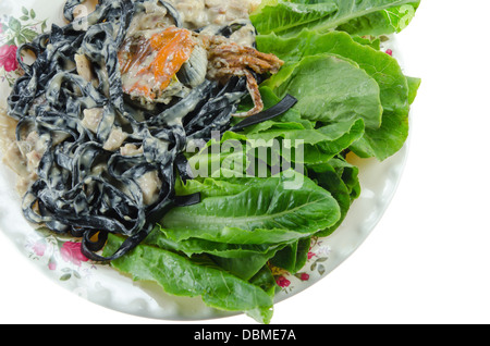 Vue de dessus des tagliatelles noires (les pâtes faites avec de l'encre de seiche) avec sauce carbonara , crabe frit et des légumes frais sur lave Banque D'Images