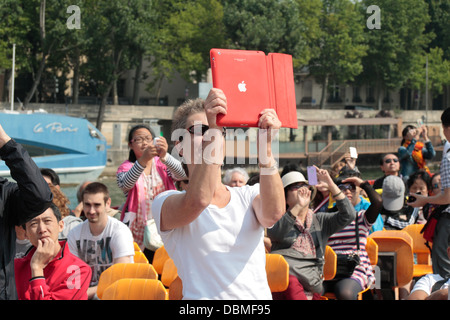 Une femme prend une photo avec un iPad sur un voyage en bateau sur la Seine, Paris, France. Banque D'Images