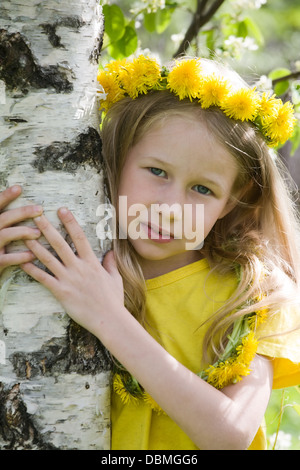 Closeup portrait of smiling little girl hugging guirlande pissenlit en tronc de bouleau Banque D'Images